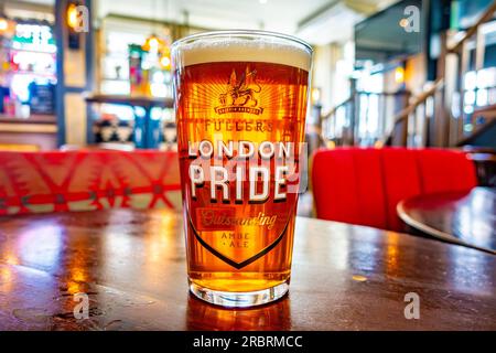 A pint of Fuller's London Pride beer on a wooden tabletop in a pub Stock Photo