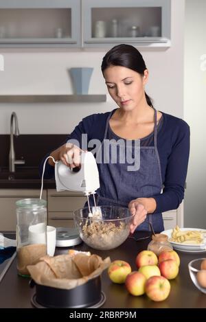 Woman using electric mixer to mix ingredients for dough of sugar, beaten  eggs, butter and flour while making cookies in the kitchen at home closeup  Stock Photo - Alamy