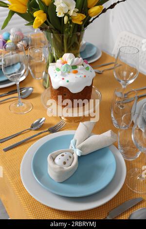 Festive table setting with painted eggs, traditional Easter cake and vase of tulips Stock Photo