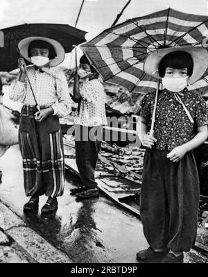 Hiroshima, Japan,  October 1, 1945 Three young Japanese girls wear masks over their noses and mouths to muffle the remnants of the odors from the dead and decaying bodies after the dropping of the atomic bomb. Stock Photo