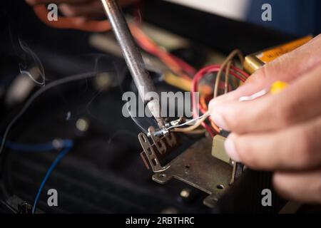 Technician using soldering iron to repairing the electronic device. Stock Photo