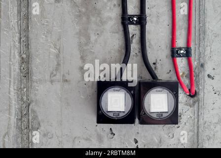 Close up concrete wall, old black and white light switch, black red cable on the wall, industrial interior design, copy space, black and red cable on Stock Photo