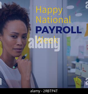 Composition of happy national payroll week text over biracial businesswoman at glass wall Stock Photo