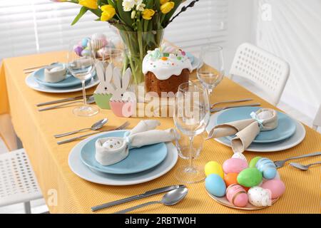 Festive table setting with painted eggs, traditional Easter cake and vase of tulips Stock Photo