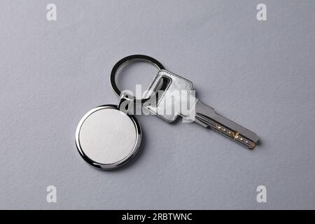 Key with metallic keychain on light grey background, top view Stock Photo