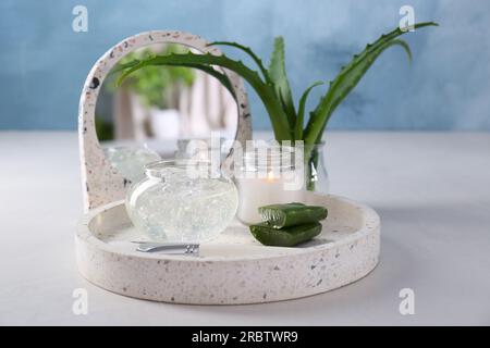 Jar of natural gel, burning candle, makeup brushes and fresh aloe leaves on white table Stock Photo