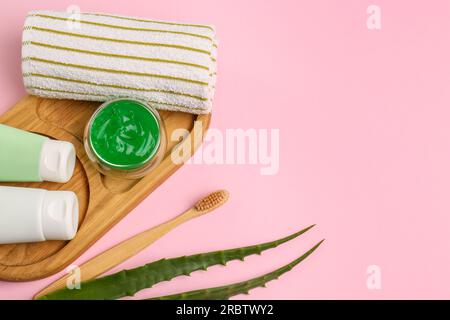 Tubes of toothpaste, fresh aloe, toothbrush and towel on pink background, flat lay. Space for text Stock Photo