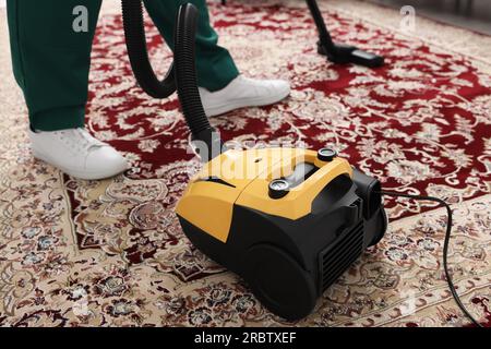 Dry cleaner's employee hoovering carpet with vacuum cleaner, closeup Stock Photo