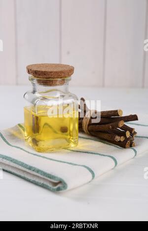 Dried sticks of licorice roots and essential oil on white table Stock Photo