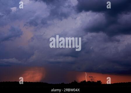 Lightning among dark clouds at sunset, the beginning of a hurricane. Stock Photo