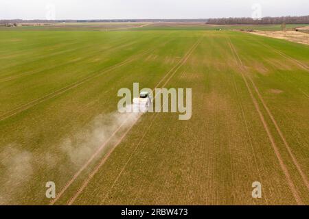 Drone photography of agricultural equipment working in field and spreading fertilizer during spring sunny day. Stock Photo