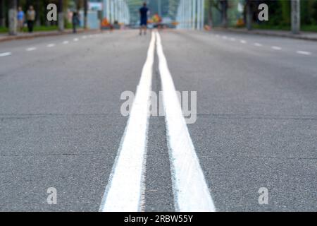 The asphalted road with two continuous white strips. The highway with a white marking. Concept long way, beginning something Stock Photo