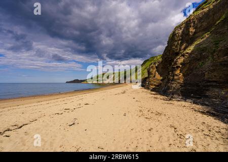 Runswick Bay beach and its pristine sandy beach exposed at low tide. A line of cliffs provide a backdrop leading to the headland at Kettleness. Stock Photo