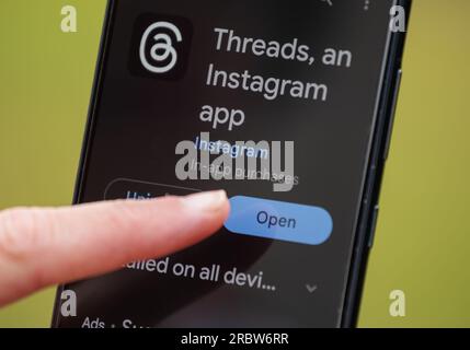Finger pressing open button on smartphone touchscreen to open the new Instagram Threads app, a social media platform by Meta. Stock Photo