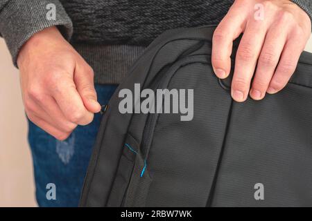 close-up. Men's hands fasten a bag. a protective folder for a laptop. The guy closes the bag Stock Photo