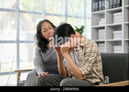 A kind and caring Asian grandma touched her grandson's head with love and kindness, trying to comfort her stressed and crying grandson at home. Family Stock Photo