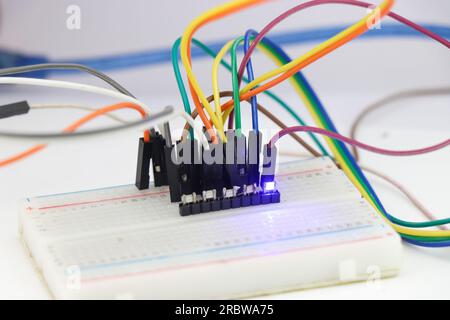 Group of SMD led on a breadboard connected with jumper wires and emitting a blue light Stock Photo