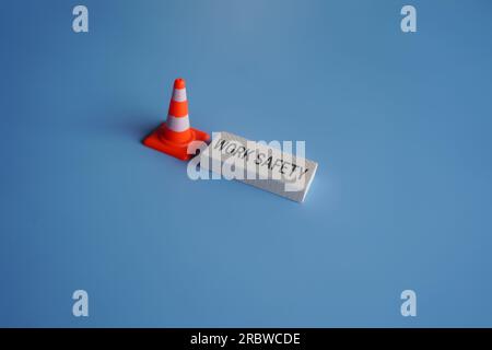 Traffic safety cone and text WORK SAFETY on blue background. Safety at workplace concept Stock Photo