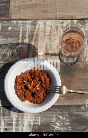 Fregola with Tomatoes and fish ragout (ball-shaped Sardinian pasta) and glass of rose wine, Sardinia, Italy, Europe Stock Photo