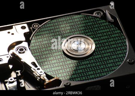 Hard disk on a black background with reflections on ones and zeros (binary code). Stock Photo