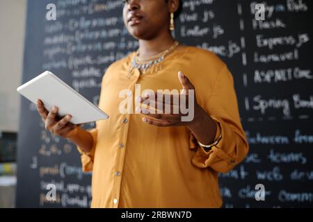 African American teacher using digital tablet to explain new material to students at lesson Stock Photo