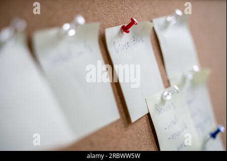 A lot of memos on cork bulletin board with pins. Tasks planning, reminders, ideas for business Stock Photo