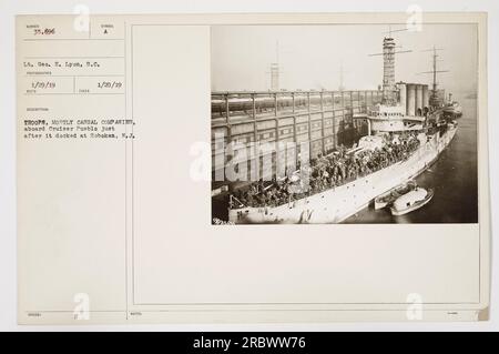 American troops, mainly composed of casual companies, disembark from the USS Pueblo at Hoboken, New Jersey, after returning from active duty. The photograph, taken on January 29, 1919, captures the soldiers as they are unloaded from the cruiser. This image has the issue number 35,696 and corresponds with the official records. Stock Photo