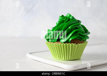 Homemade chocolate cupcake with green whipped cream on white background. Close up. Happy Birthday celebration. Stock Photo