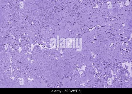 Concrete wall with old cracked, peeling flaking purple paint. Weathered rough painted surface with patterns of cracks and peeling, grunge, aged textur Stock Photo