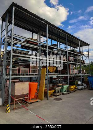 Construction site stacked storage shelves with pallets, cement mixers and raw materials. Exterior shot, sunny blue sky, no people. Stock Photo