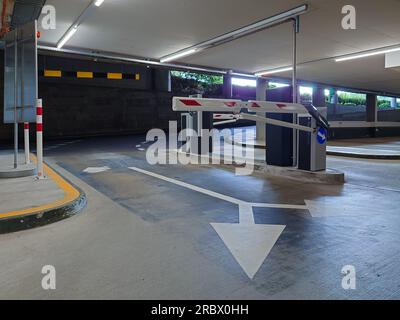 Underground large car park entrance and exit lanes with ticket dispensers and barriers. No people. Stock Photo