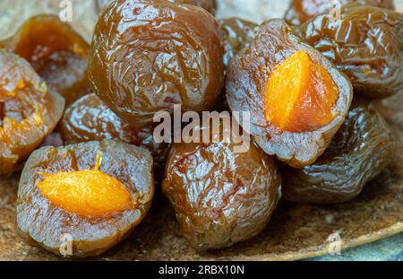 Close-up of Flavored preserved chinese plums (Preserved fruits) on wooden background. Its flavour has sour, salty and sweet taste. Space for text, Sel Stock Photo
