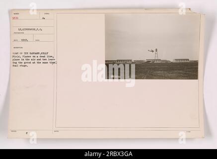 Planes lined up on the tarmac at Kelly Field with hangars in the background. One plane is currently in the air while two others are preparing to take off simultaneously, showcasing a dual stage takeoff. This photograph was taken by Lt. Kingsmore in 1918 and is labeled as Number 9570. Stock Photo