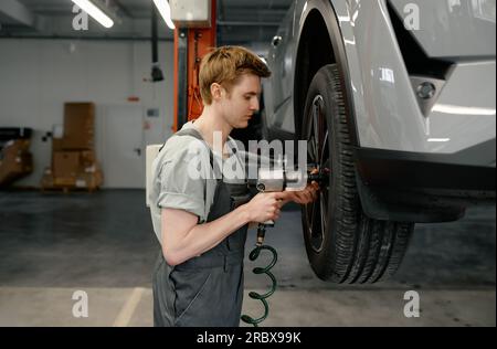 Professional man mechanic changing car wheel using electric drill Stock Photo