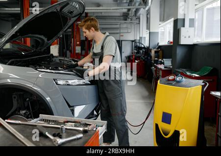 Man auto mechanic entering data for refilling of car air conditioner Stock Photo