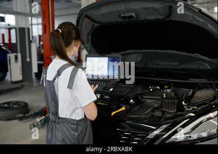 Back view on woman auto engineer doing computer diagnostic Stock Photo