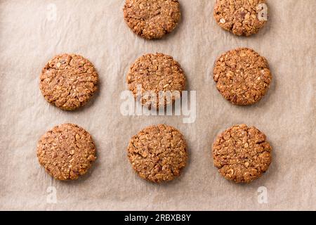 Healthy oatmeal cookies with dates, nuts and flaxseed on baking paper, top view. Delicious homemade vegan baking. Stock Photo