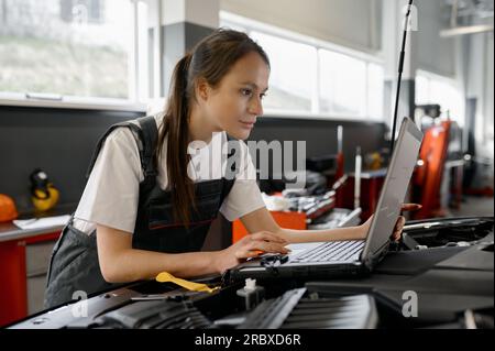 Back view on woman auto engineer doing computer diagnostic Stock Photo