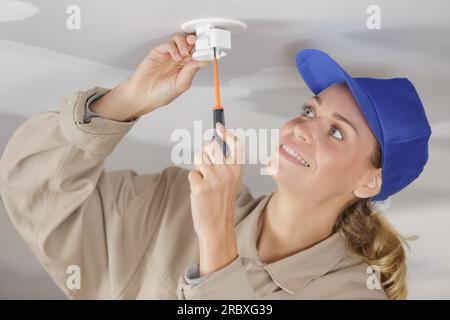 a woman installing light fitting Stock Photo