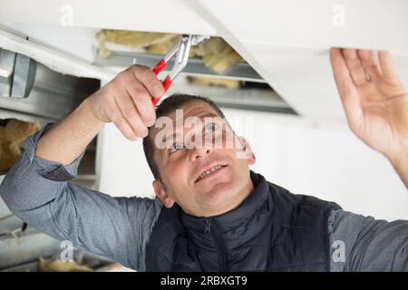 male builder using pliers through roof panel Stock Photo