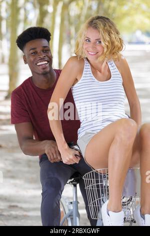 man carrying girlfriend in bike basket Stock Photo