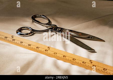 Vintage rusty scissor and wooden ruler on top of old white fabric. Stock Photo