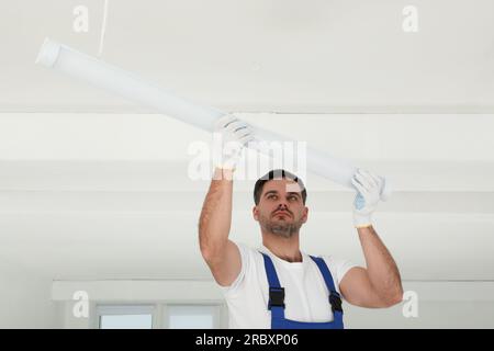 Electrician installing led linear lamp indoors. Ceiling light Stock Photo