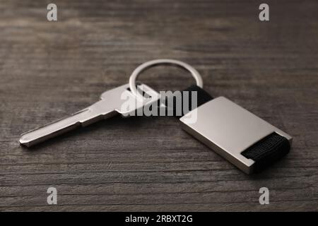 Key with metallic keychain on wooden background, closeup Stock Photo