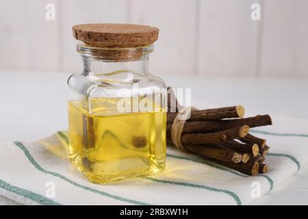 Dried sticks of licorice roots and essential oil on white table, closeup Stock Photo