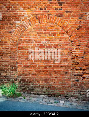 A bricked up doorway arch on the side of an old factory building. Stock Photo