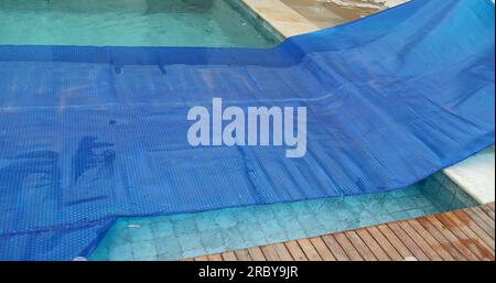 Man removing swimming pool cover and folding protector Stock Photo