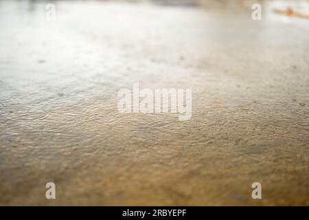 This stock photo shows a close-up of rainwater drops falling onto a concrete floor. Stock Photo