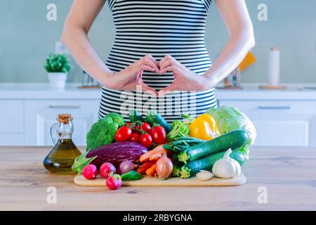 Fresh vegatables on a wooden table with woman  doing love heart with her hands - healthy eat lifestyle concept for vegetarian or diet weight loss acti Stock Photo