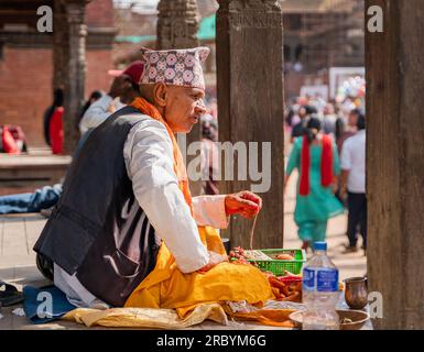 Kathmandu, Nepal - August 12, 2022: People of Nepal. Man in traditional nepalese clothes sitting on the floor in a temple Stock Photo